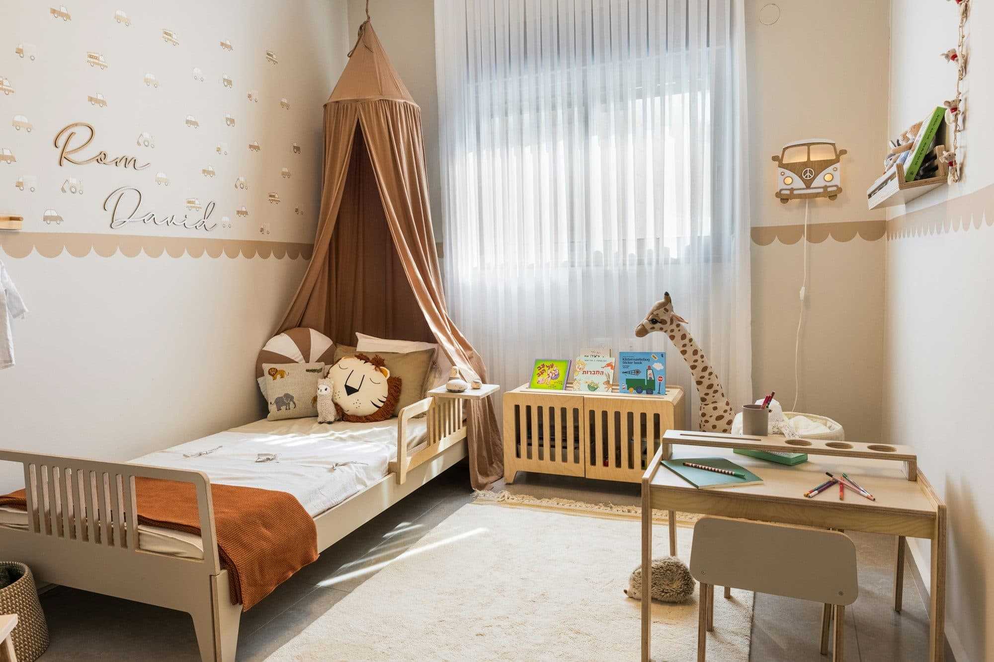 A bright children's room with a wooden bed, a canopy and a small desk